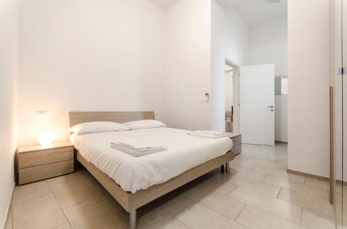 a white bedroom with a large bed with white sheets at S.Felice Apartments in Bologna