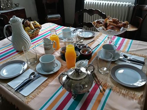 a table with plates and utensils and orange juice at Castel La Bergerie in Laglorieuse
