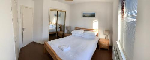 a bedroom with a bed with white sheets and a mirror at Aberdeen Serviced Apartments - Bloomfield in Aberdeen