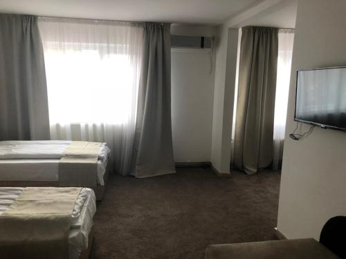 a hotel room with two beds and a flat screen tv at Gros Hotel - Leskovac in Leskovac