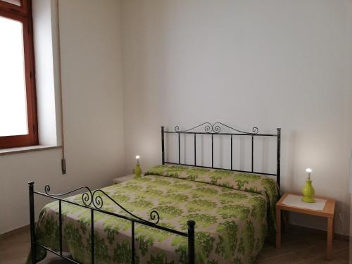 a bedroom with a bed with a green bedspread and a table at APPARTAMENTO IN CENTRO in Marsala