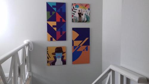 three framed paintings on a wall in a hallway at Hostel Criativo do Sabugueiro in Sabugueiro