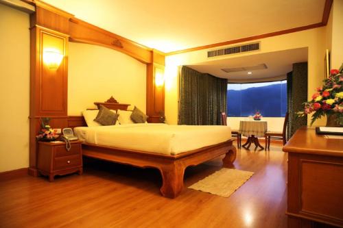 a bedroom with a bed and a room with a table at Furama Chiang Mai in Chiang Mai
