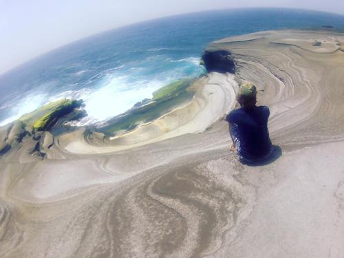 a person sitting on the sand near the ocean at bed & breakfast Regina in Tarrafal