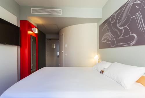 a bedroom with a large white bed and a painting on the wall at Ibis Elche in Elche