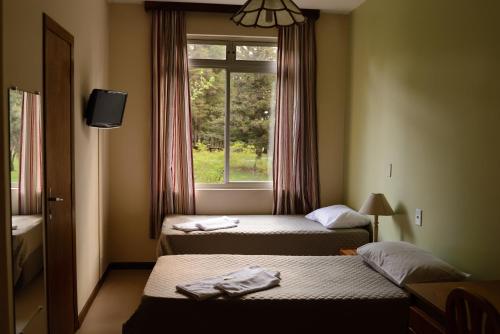 a hotel room with two beds and a window at Pousada Betânia in Curitiba