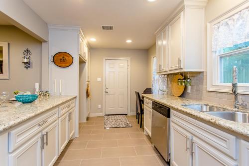 a kitchen with white cabinets and a sink and a window at The Blue Door Bungalow - Luxury Home Downtown Houston in Houston