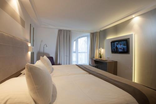 a hotel room with a large bed and a television at Hotel Erzgiesserei Europe in Munich