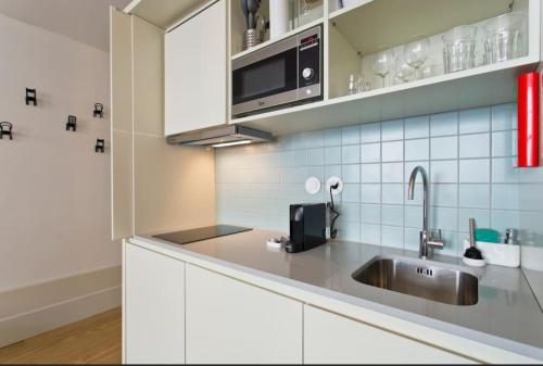 eine Küche mit einer Spüle und einer Mikrowelle in der Unterkunft Vitoria Studio Residence II - Downtown in Porto