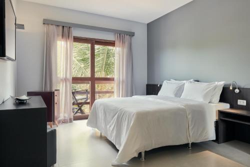 a bedroom with a large white bed and a window at Rox Hotel in Jericoacoara