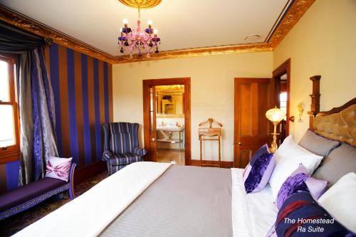 a bedroom with a bed and a chair and a chandelier at Tracy's Boutique B&B Farmstay in Wellsford