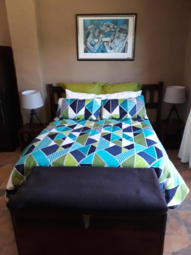 a bed with a colorful comforter in a bedroom at Rugare Sweet Dreams Holiday Cottage in Curryʼs Post