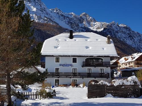 a building covered in snow with mountains in the background at La Girandole Chambre d'hôtes et Location d'appartement in Arvieux
