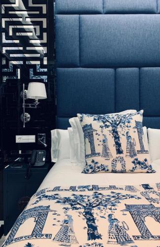 a bedroom with a bed with a blue head board at Hotel Casa Palacio María Luisa in Jerez de la Frontera