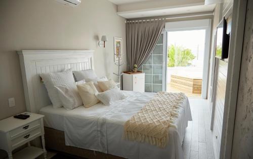 a bedroom with a large white bed and a balcony at Solar Beach Hotel in Florianópolis