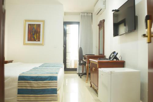 a hotel room with a bed and a desk and a television at Hôtel Millennium Kamissa in Bamako