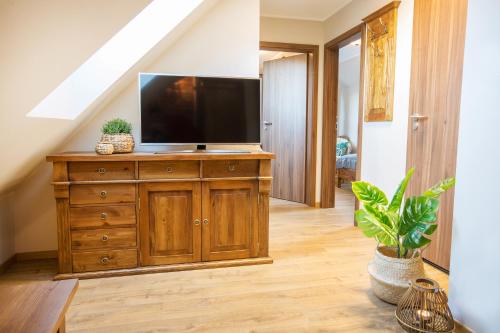 a living room with a television on a wooden dresser at Willa Ostoja Wellness in Świeradów-Zdrój