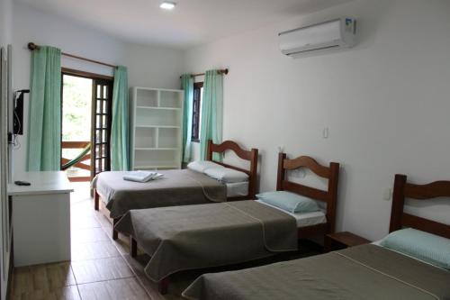 a hotel room with three beds and a window at Pousada Leão do Mar in Abraão