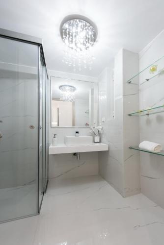 a white bathroom with a sink and a shower at Despina's Luxury apt downtown in Heraklio