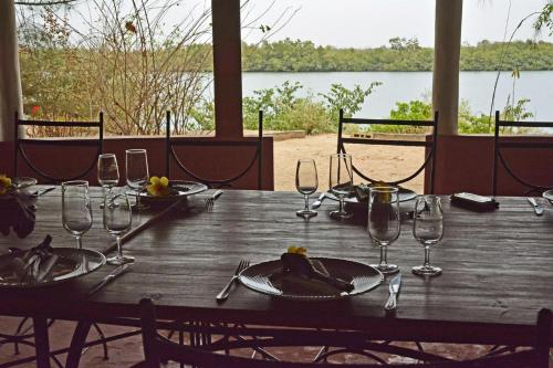 a wooden table with wine glasses and food on it at Campement île d'Egueye in Diakène Ouolof