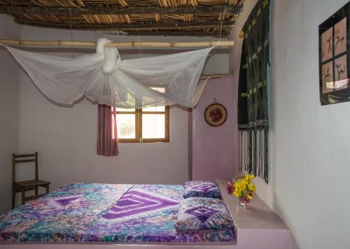 een slaapkamer met een hemelbed en een raam bij Campement île d'Egueye in Diakène Ouolof