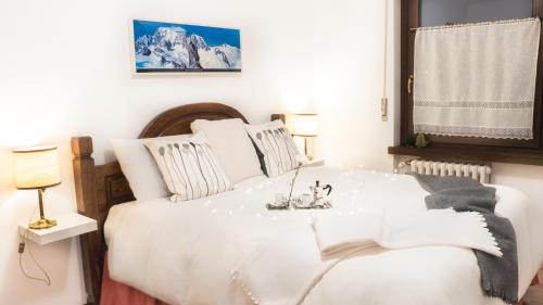 una camera da letto con un grande letto bianco e un tavolo di L'Atelier du Temps - PanoramAlps Apartment a Courmayeur