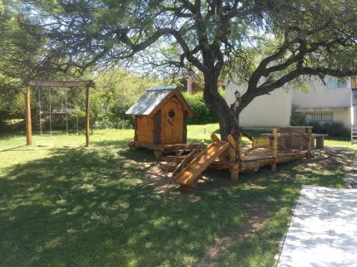 una casa de juegos de madera bajo un árbol en un patio en Casa en Villa Los Aromos en 