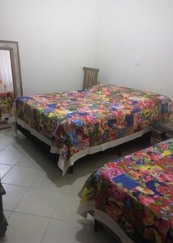a bedroom with two beds with a colorful comforter at Seo Chico Sobradinho in São Sebastião
