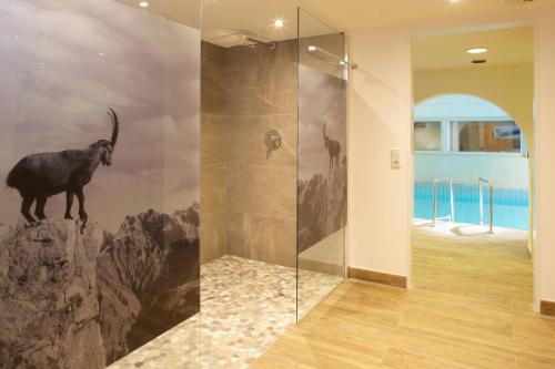 a bathroom with a mural of a goat on the wall at Hotel Menning ***S in Oberstdorf