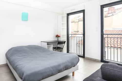 a bedroom with a bed and a desk and windows at 204 - Appartement Moderne et Lumineux - Jeanne d'Arc, Toulouse in Toulouse