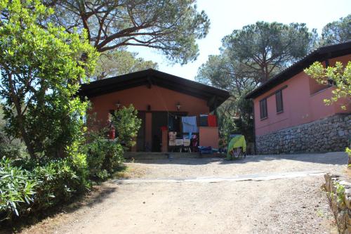a house with a dirt road in front of it at Camping Lacona Pineta in Capoliveri