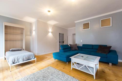 uma sala de estar com um sofá azul e uma cama em Calçada do Combro em Lisboa