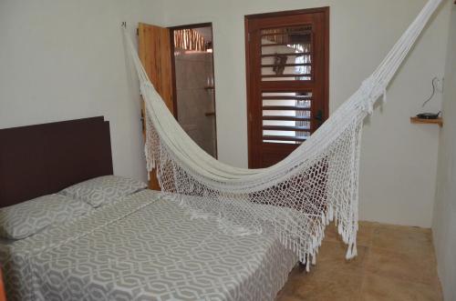 a hammock in a room with a bed and a window at Os Navegantes B in Guajiru