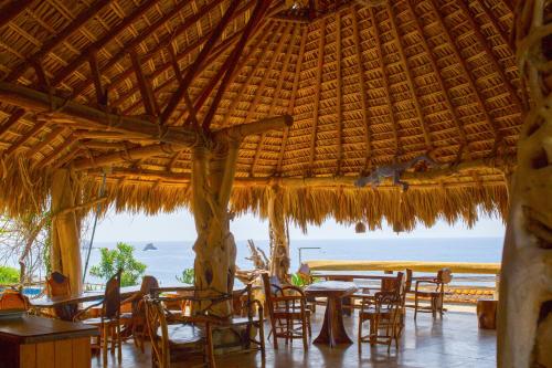 a restaurant with tables and chairs and a view of the ocean at Cabañas Las 3 Marias in San Agustinillo