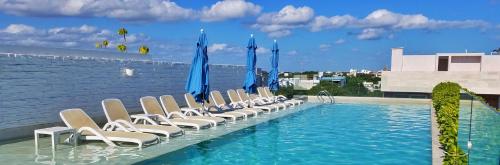 una piscina con tumbonas y sombrillas azules en Anah Suites by Las Flores, en Playa del Carmen