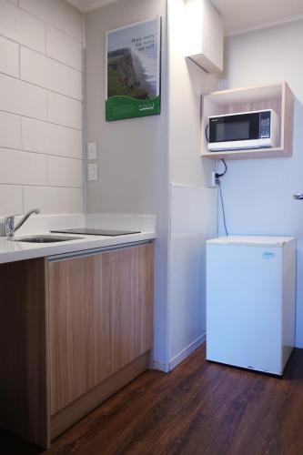 a kitchen with a refrigerator and a microwave at A1 Kaikoura Motel & Apartment in Kaikoura