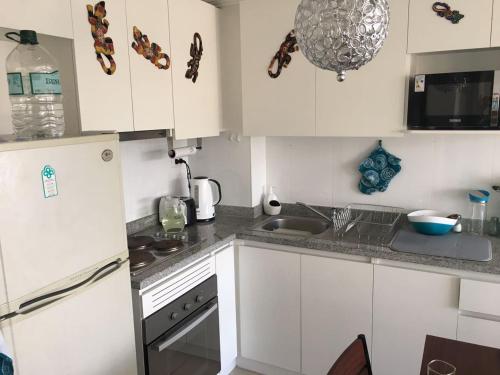 una piccola cucina con armadi bianchi e lavandino di Condominio Papudo Laguna, Avenida El Estero 203 a Papudo