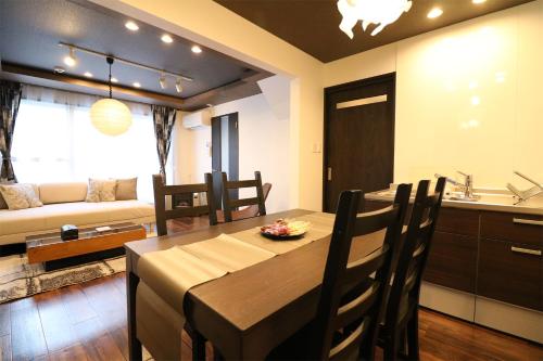 札幌的住宿－One’s Villa Sapporo House，厨房以及带桌子和沙发的用餐室。