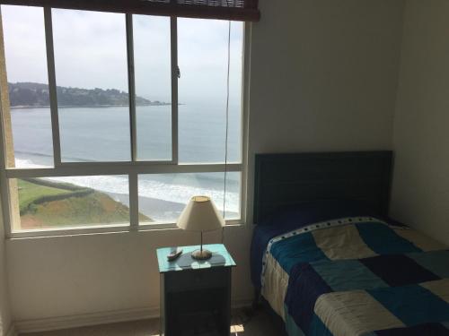 a bedroom with a bed and a view of the ocean at Apartamento 630 Costa Quilen in Horcón