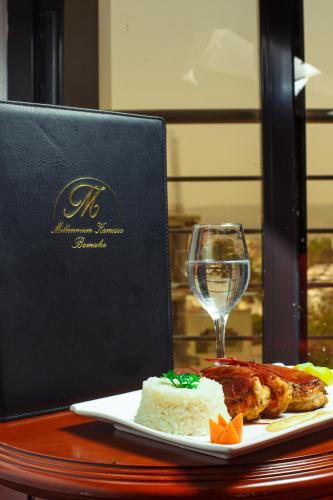 a table with a plate of food and a glass of wine at Hôtel Millennium Kamissa in Bamako