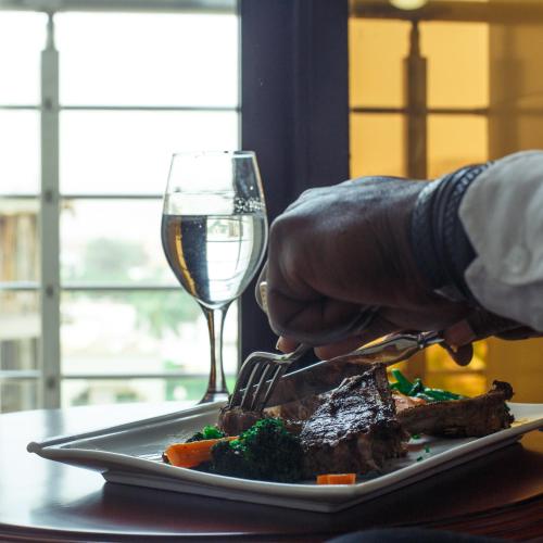 a plate of steak and a glass of wine at Hôtel Millennium Kamissa in Bamako