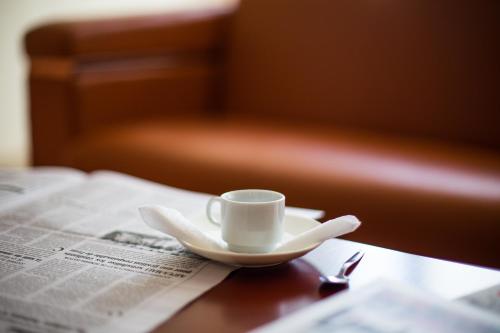 a cup and saucer on a table with a newspaper at Hôtel Millennium Kamissa in Bamako