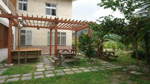 a picnic table and benches under a wooden pergola at Ho Hai Yan Homestay in Chenggong