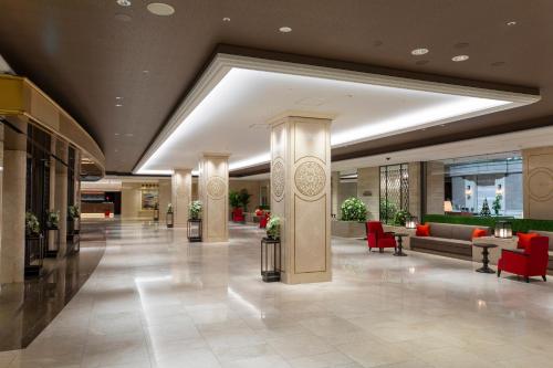 a lobby of a hotel with red chairs and tables at Nagoya Tokyu Hotel in Nagoya