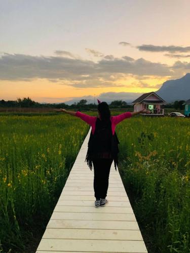 a woman walking down a path in a field at Ban Thung Talay Mok Chiangdao in Chiang Dao