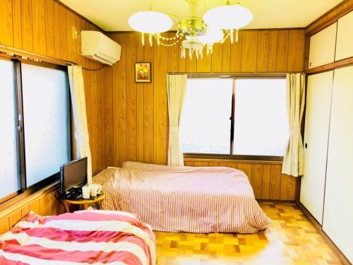 una camera con due letti, una televisione e finestre di Ibusiki Chinese Minshuku a Ibusuki
