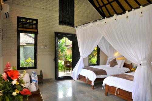 a bedroom with two beds with white drapes at Hidden Paradise Cottages in Amed
