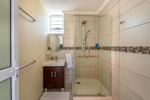 a bathroom with a shower and a sink at Pro Moni's Guesthouse in Muizenberg