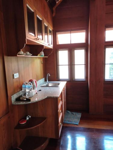 a kitchen with wooden walls and a sink and windows at Mina Garden Villa Resort in Chiang Mai