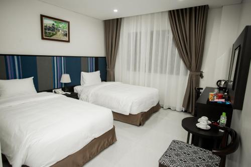 a hotel room with two beds and a table at Max Boutique Hotel in Cao Bằng